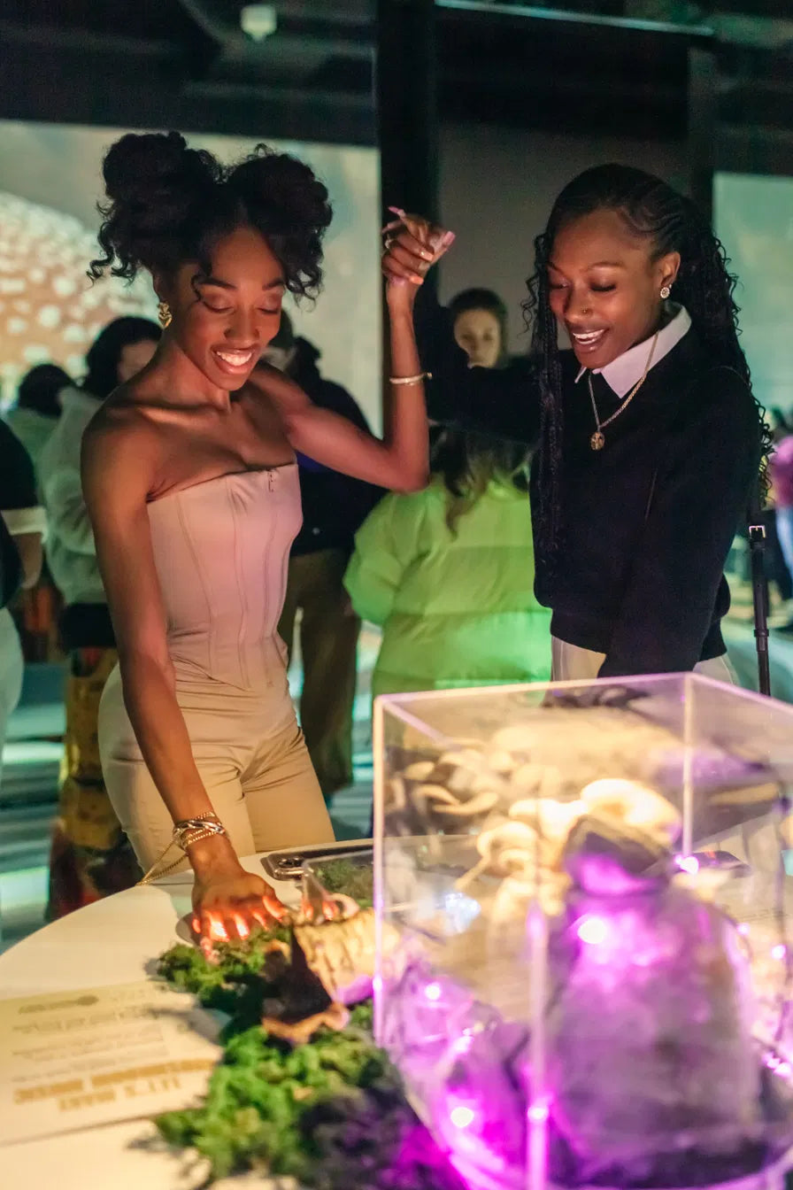 Two visitors interacting with a fruiting-block station